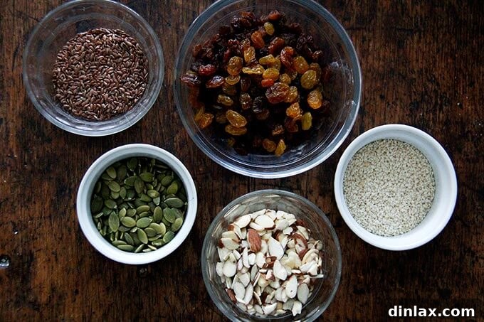 Three Seed Crisps 5 A vibrant mix of three types of seeds, sliced almonds, and plump golden raisins in a bowl, ready to be incorporated into the cracker dough.