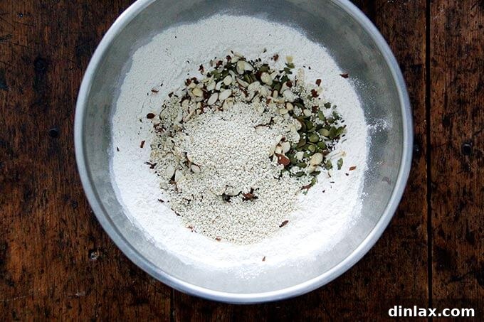 Three Seed Crisps 6 All dry ingredients for the three-seed crackers, including flour, spices, seeds, nuts, and dried fruit, thoroughly mixed together in a large bowl.