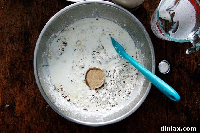 Three Seed Crisps 8 Wet ingredients, including buttermilk, maple syrup, and brown sugar, being added to the bowl of dry ingredients for the three-seed cracker batter.