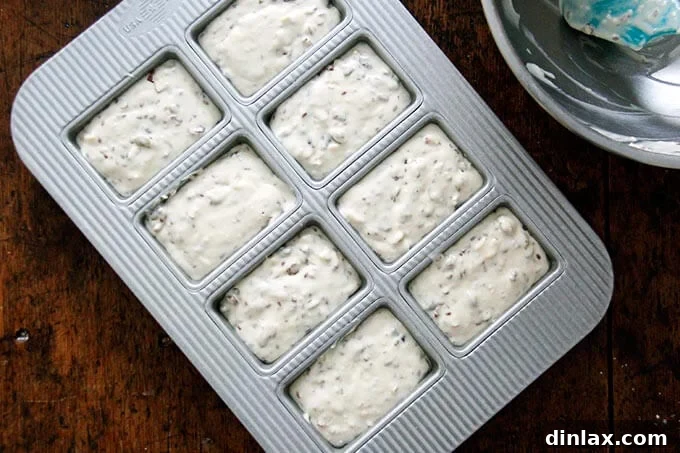 Three Seed Crisps 10 An 8-compartment mini loaf pan, meticulously filled with the three-seed cracker batter, ready for its initial bake.