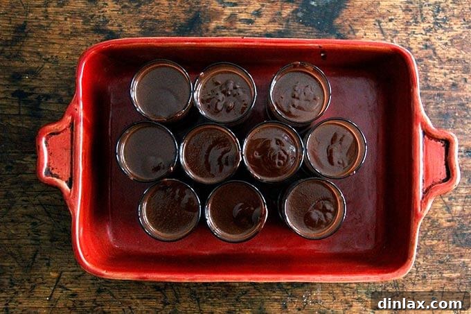A 9x13-inch baking pan filled with small glasses filled with the chocolate pot de creme.