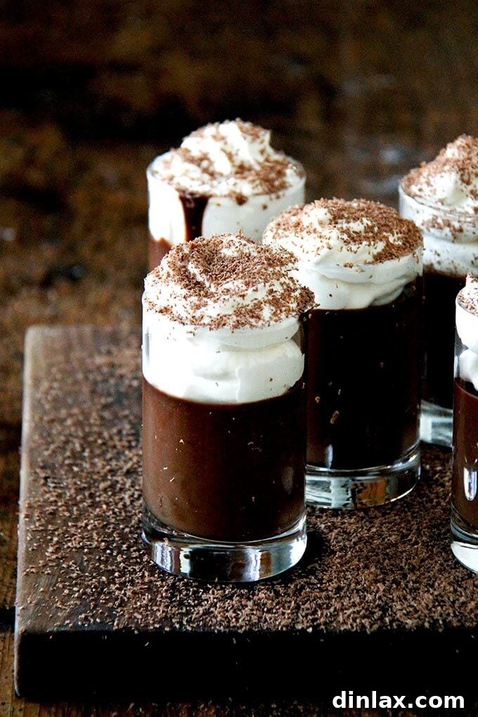 A board filled with small glasses filled with chocolate pot de creme and topped with homemade whipped cream.