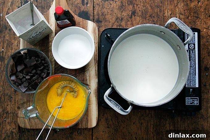 Overhead shot of a pot of cream on a portable burner aside other ingredients for stovetop pot de creme. 