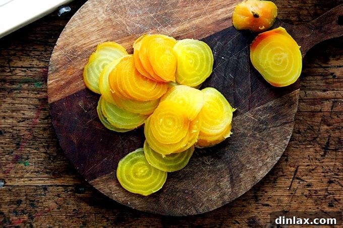 Thinly sliced, cooked beets arranged on a cutting board.