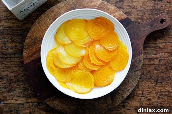 Salted beets in a bowl, being doused with white balsamic vinegar.