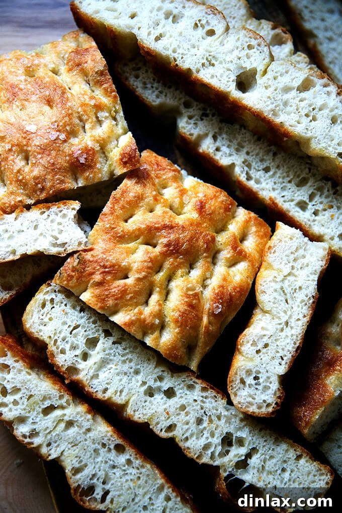 Just-baked focaccia bread resting on a wooden cutting board, ready to be sliced.