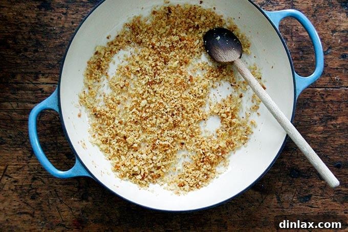 An overhead view of a large skillet brimming with golden-brown, olive oil-toasted breadcrumbs, radiating a delicious aroma.