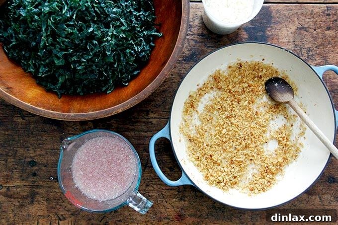 An overhead view showcasing all the prepared components for the kale salad: finely chopped kale, grated Parmesan, golden toasted breadcrumbs, and the vibrant shallot vinaigrette, arranged neatly for assembly.
