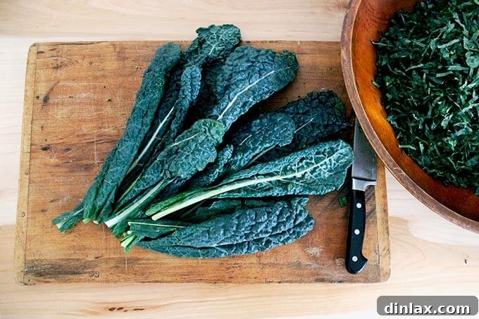 Fresh Tuscan Kale leaves neatly arranged on a wooden cutting board, ready for preparation.
