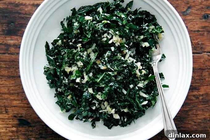 A vibrant bowl of tossed kale salad, perfectly coated with shallot vinaigrette and adorned with toasted breadcrumbs and grated Parmesan, ready to be enjoyed.