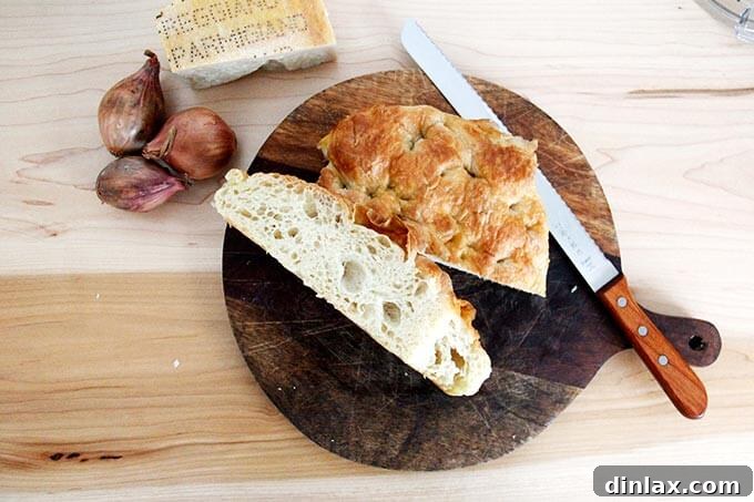 A piece of delicious, day-old focaccia bread resting on a wooden cutting board, ready to be transformed into breadcrumbs.