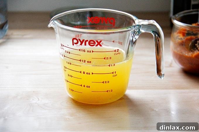 Instant Pot Harissa Rice with Sweet Dates and Zesty Orange 13 A clear liquid measuring cup containing freshly squeezed orange juice topped up with water to the required 1 1/3 cup mark, ready to be added to the rice.