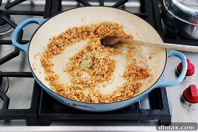 Instant Pot Harissa Rice with Sweet Dates and Zesty Orange 10 A skillet with Moroccan rice in the making, showing the rice being stirred with the harissa and onion mixture.
