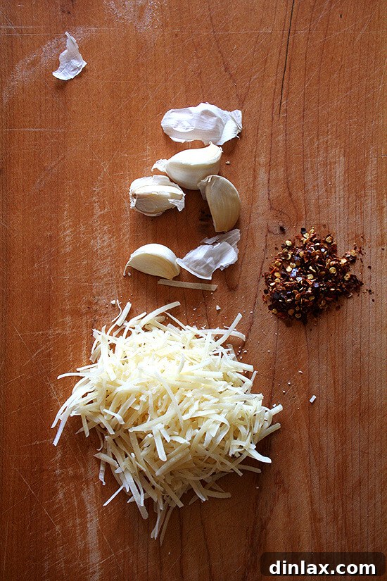 A trio of essential flavor enhancers: grated cheese, minced garlic, and vibrant red pepper flakes.