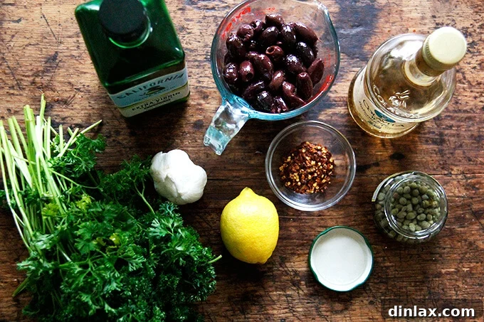 Zesty Olive Tapenade with Capers and Fresh Parsley 3 An overhead shot of the ingredients to make black olive tapenade, including olives, lemon, garlic, capers, and parsley.