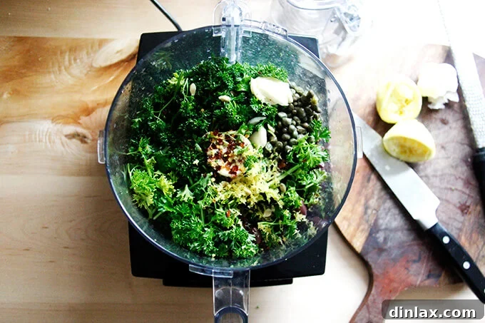 Zesty Olive Tapenade with Capers and Fresh Parsley 4 An overhead shot of a food processor holding the initial ingredients to make black olive tapenade, excluding half the parsley and olive oil.