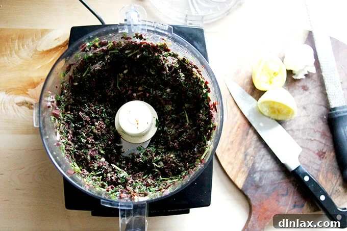 Zesty Olive Tapenade with Capers and Fresh Parsley 5 A food processor holding finely chopped, coarse black olive tapenade mixture, showing good texture.