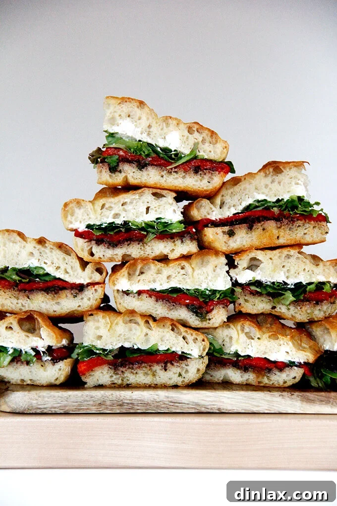 Zesty Olive Tapenade with Capers and Fresh Parsley 9 A stack of beautifully prepared slab sandwiches featuring black olive tapenade, roasted red peppers, whipped honey goat cheese, and fresh lettuce.