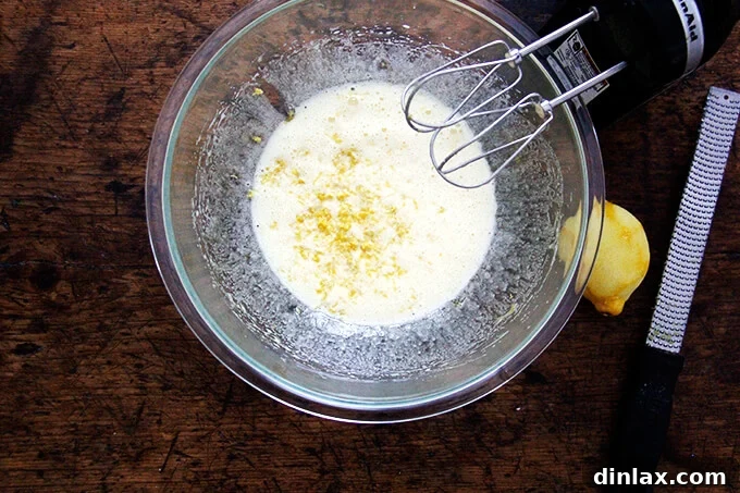 An overhead shot of eggs beaten with sugar and lemon zest, showing the flecks of yellow zest.