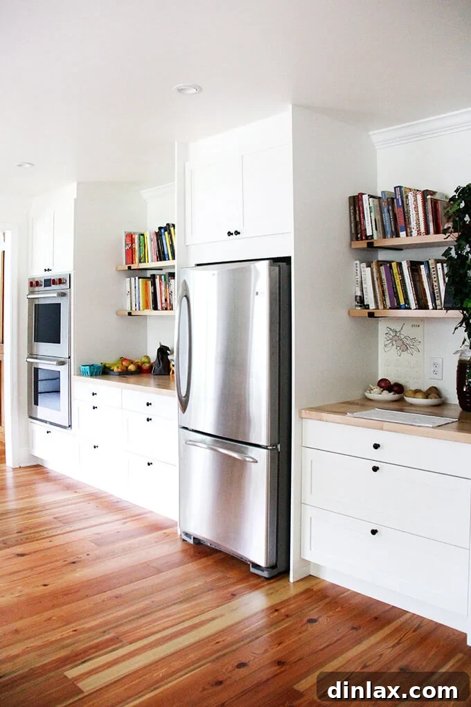 Corner of a minimalist kitchen showing shaker cabinets, butcher block countertops, and a clear counter space.