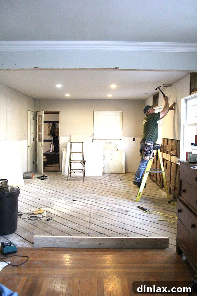 Drywall sheets being installed on kitchen walls, transforming exposed studs into smooth surfaces