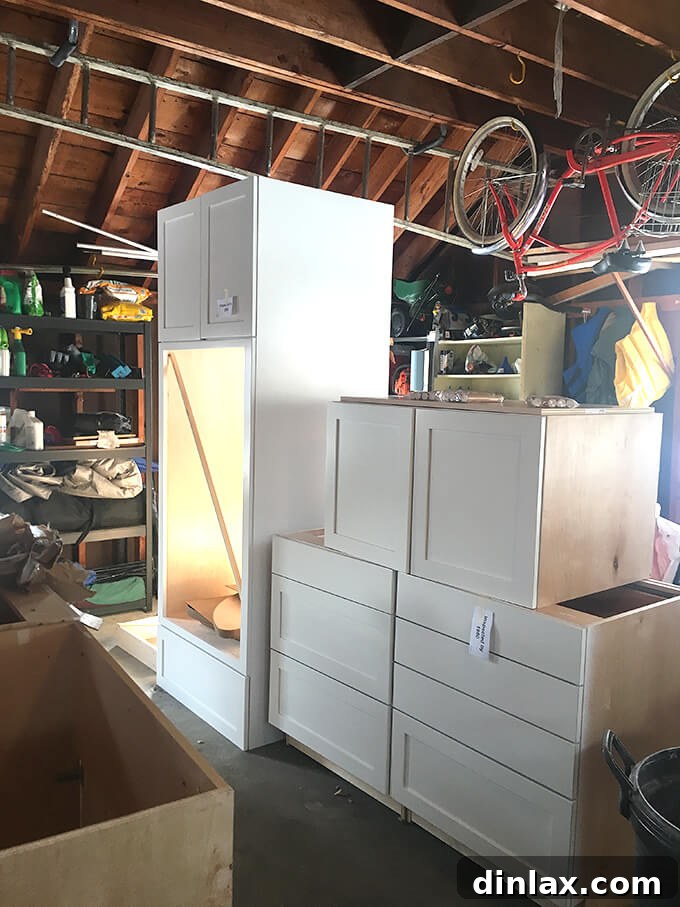 Kitchen cabinets being staged and arranged in a garage to visualize the layout before installation