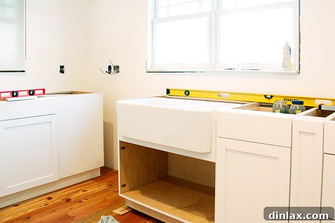 New kitchen sink being installed, including plumbing connections for water supply and drainage