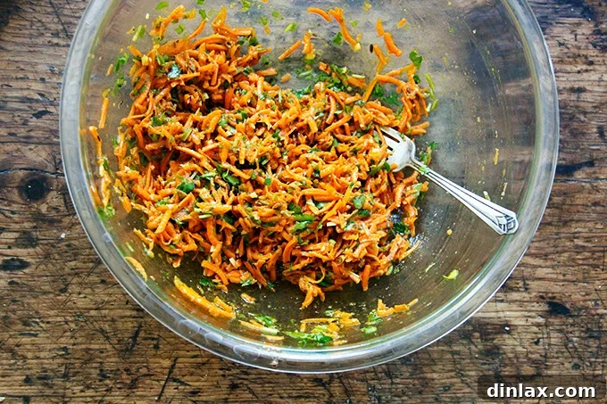 A bowl of Moroccan carrot salad, fully tossed with harissa dressing and fresh herbs, ready to be served.