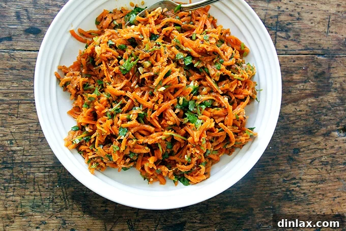 A close-up of a bowl of freshly prepared Moroccan carrot salad with harissa and herbs.