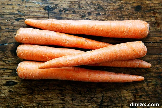 Fresh carrots on a wooden cutting board, ready for shredding.