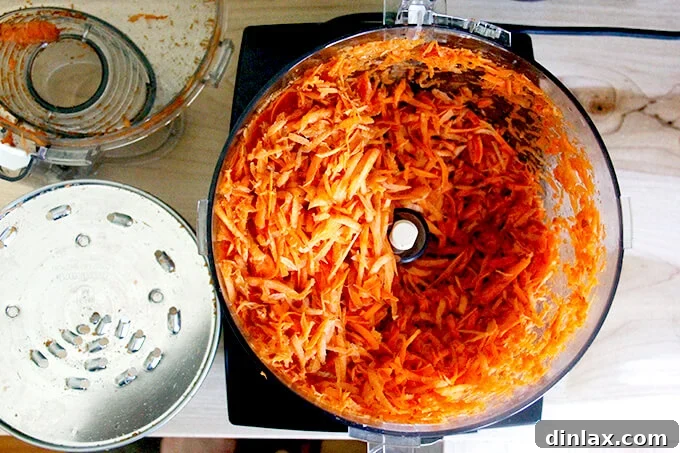 Shredded carrots in a food processor bowl, ready to be mixed.