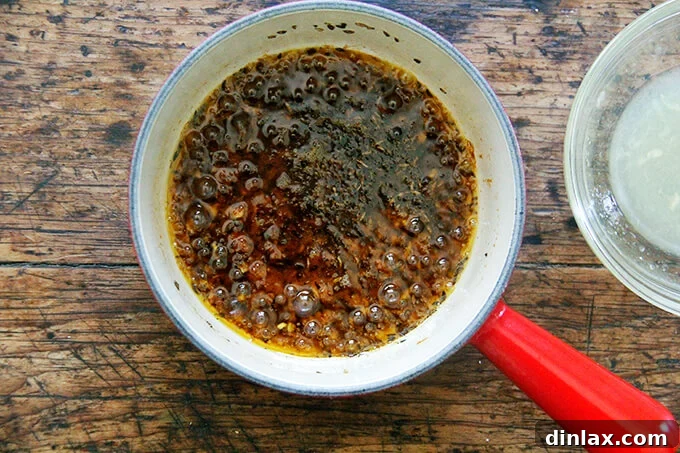 A warm harissa dressing simmering in a saucepan, releasing aromatic steam.