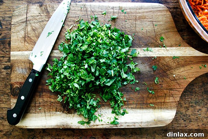 Finely minced fresh cilantro piled on a wooden board, ready to be added to the salad.