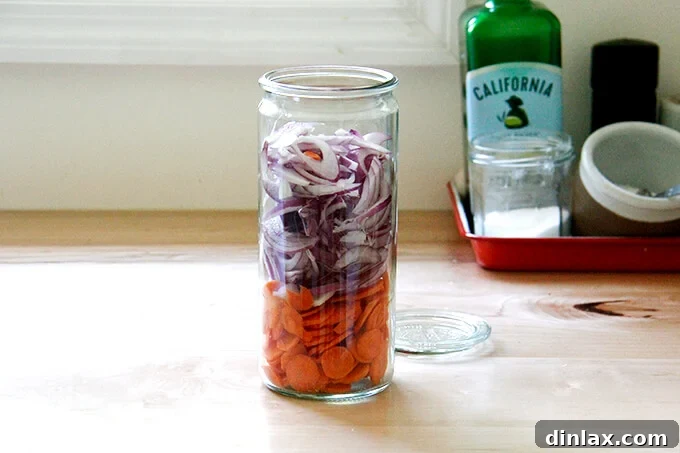 A jar filled with onions and carrots. 