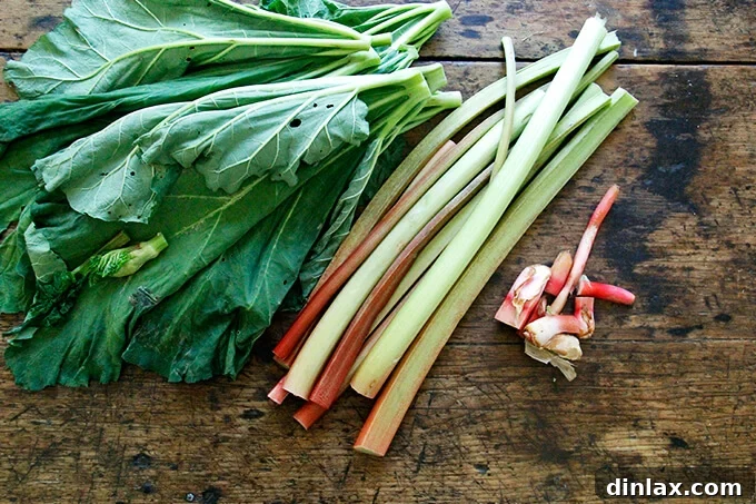 Rustic Rhubarb Frangipane Galette 3 Freshly cut rhubarb stalks and green leaves neatly arranged on a wooden cutting board.
