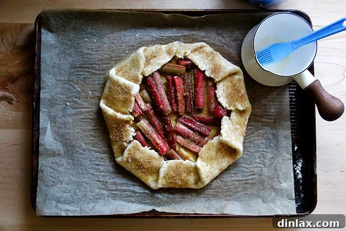Rustic Rhubarb Frangipane Galette 24 An assembled galette on a sheet pan, with the crust brushed with melted butter and generously sprinkled with turbinado sugar, ready for baking.