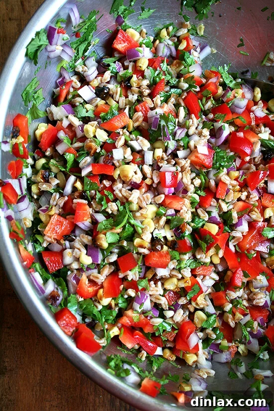 Hearty summer farro salad with roasted corn, vibrant red peppers, and onions.