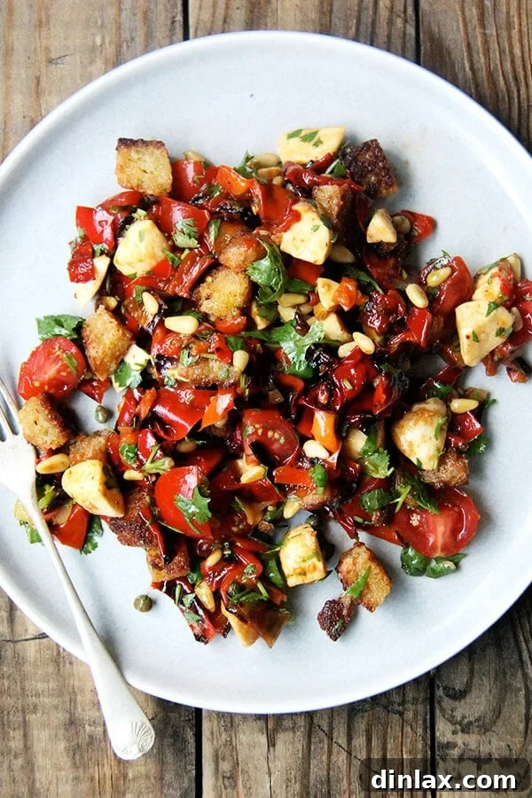 Delicious panzanella salad featuring 'magic' roasted peppers, herbs, capers, and pine nuts.