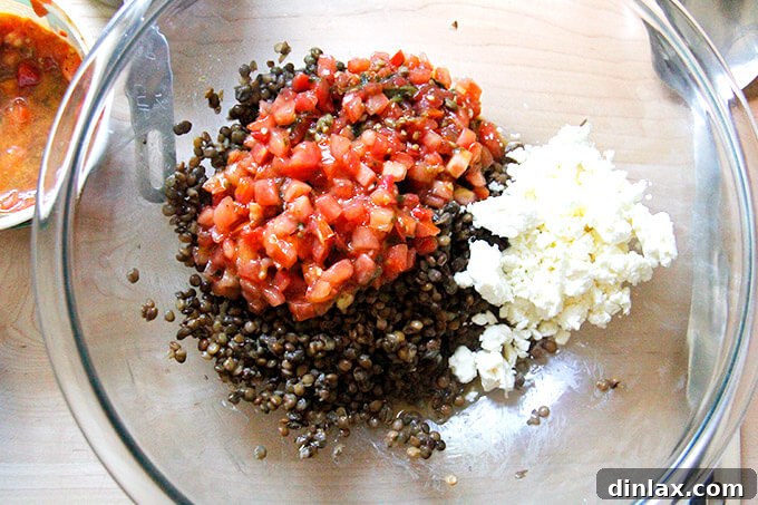 All three ingredients – cooked lentils, bruschetta sauce, and crumbled feta – placed together in a large mixing bowl, ready for tossing.