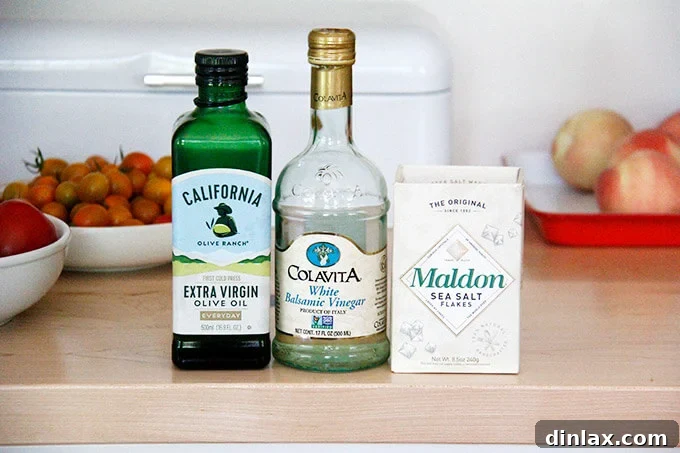 The dressing ingredients laid out on a board: Colavita white balsamic vinegar, California Olive Ranch olive oil, and Maldon sea salt. Quality ingredients for a flavorful dressing.