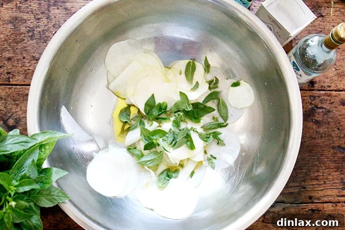 A large bowl filled with thinly shaved kohlrabi, now mixed with salt, olive oil, vinegar, and fresh herbs. Ready for the final touch.