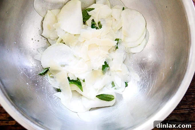 The large bowl of kohlrabi salad, now with the addition of shaved parmesan cheese, ready for a final toss. Completing the flavor profile.