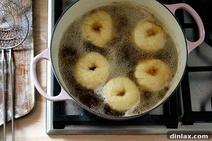 Bagels actively boiling in a pot of water, showing the bubbling process that helps create their chewy texture.