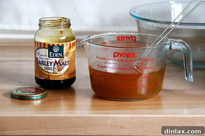 A jar of dark, viscous barley malt syrup, a key ingredient for authentic bagel flavor and texture.