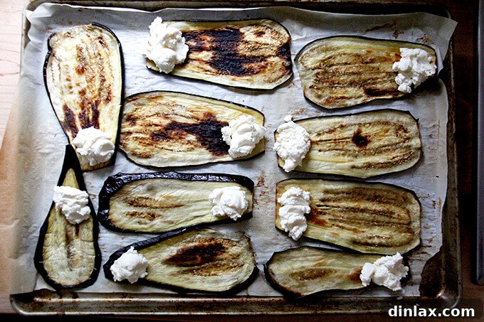 Ricotta cheese filling being spooned onto roasted eggplant slices.