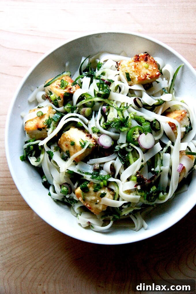 A bowl of rice noodles with herbs and nuoc cham, garnished with fresh ingredients.