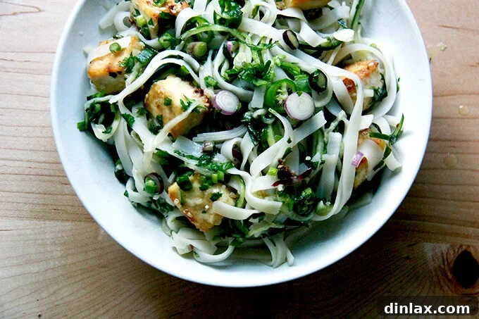A bowl of rice noodles tossed with nuoc cham, cucumbers, herbs, and crispy tofu.