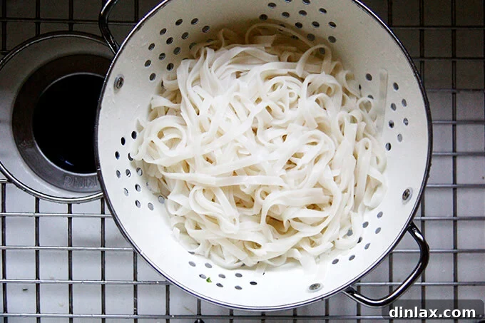 A strainer filled with cooked rice noodles.