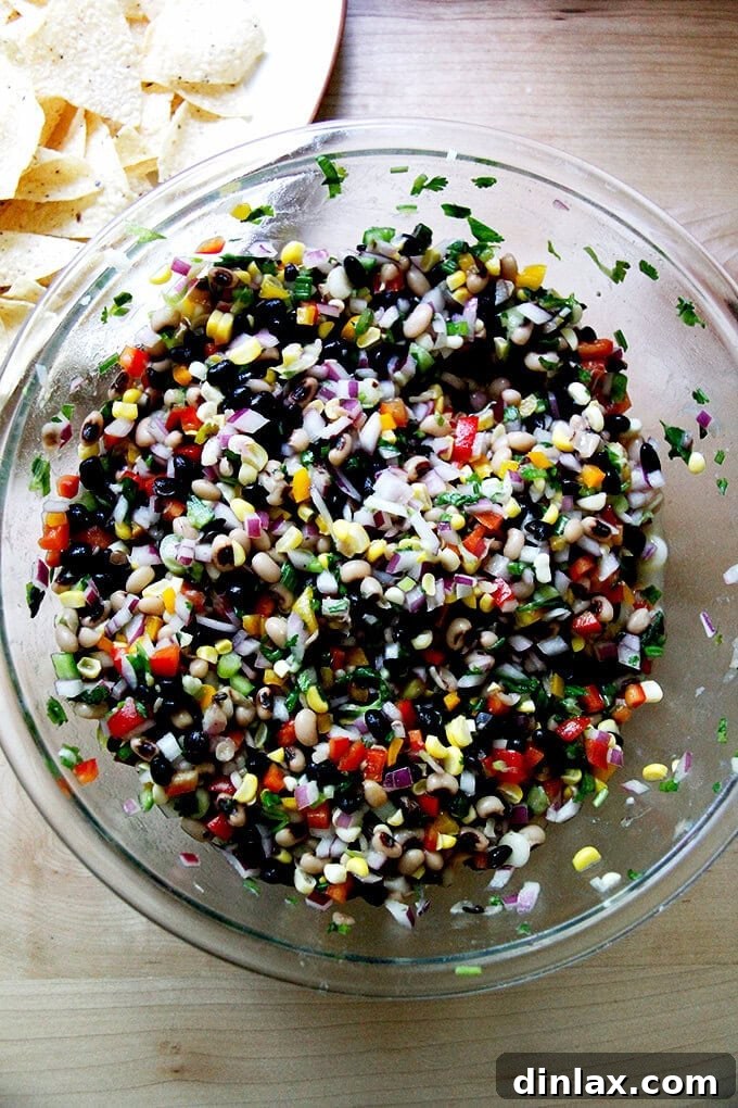 A large serving bowl generously filled with freshly prepared Texas Caviar, surrounded by crispy tortilla chips, inviting guests to dig in.
