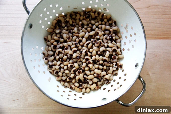 A colander full of freshly rinsed black-eyed peas, highlighting the draining process before mixing.